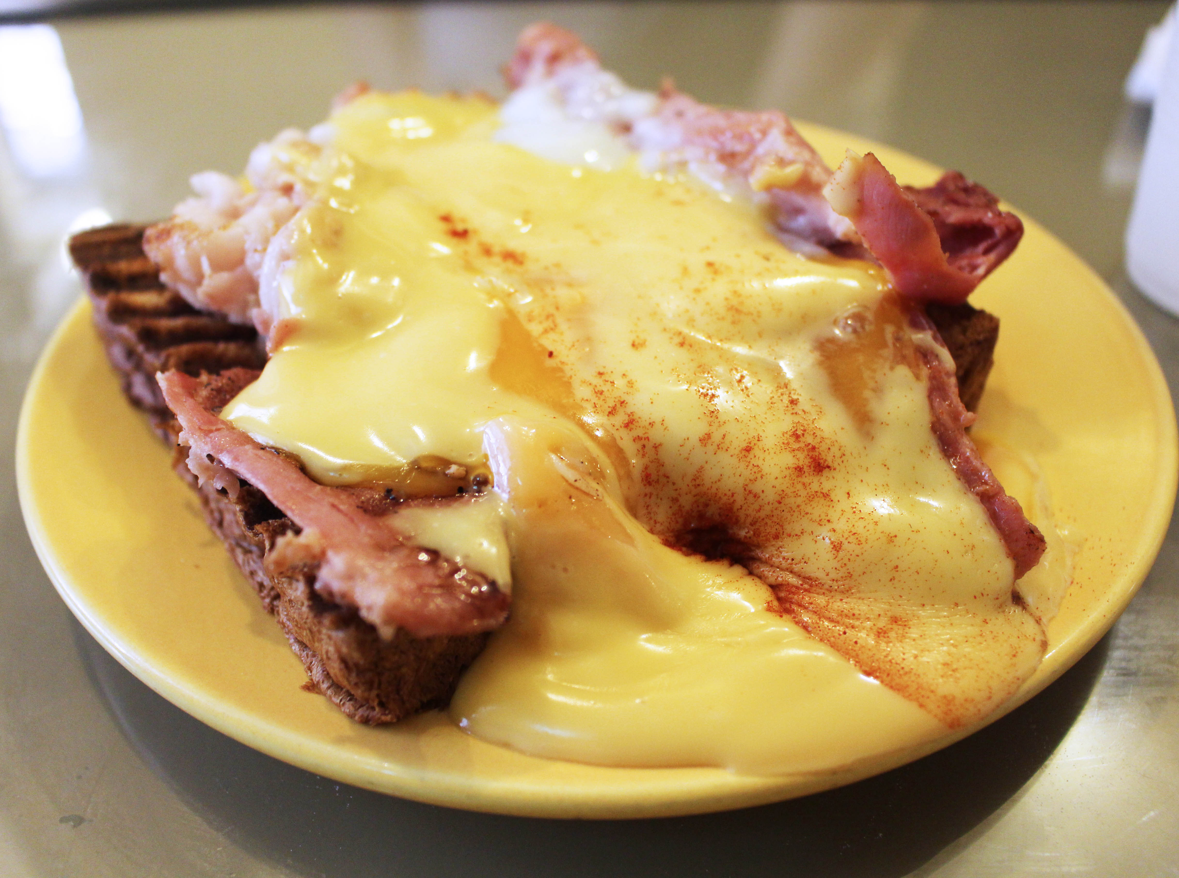 Overflowing eggs with hollandaise sauce atop pieces of ham and toasted bread